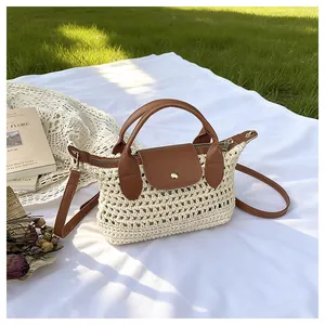 Detail van geweven stro handtas met bruine lederen flap op een picknickkleedje