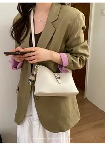 Chic beige lychee grain leather underarm bag with silver buckle and plush ball pendant