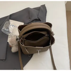 Vista dall'alto borsa a secchiello in pelle marrone con pochette e ciondolo peluche