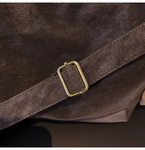 Detail of vintage matte brown shoulder bag featuring an antique metal buckle and textured leather strap