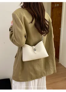 Detail of cream white pebbled leather shoulder bag with silver twist lock on olive coat
