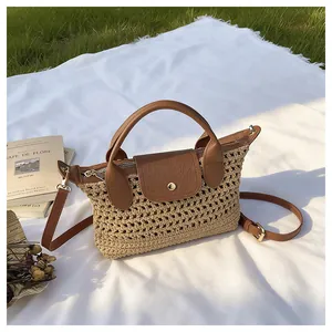 Detail van geweven strohandtas met bruine leren flap en handvat op picknickkleed