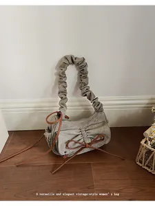 Detail view of khaki pleated baguette bag with dark brown bow and textured canvas fabric