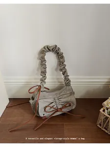 Detailed view of the pleated bow design and vintage canvas texture on this baguette bag