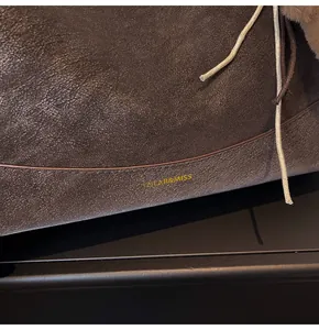 Detail shot of vintage dark brown pebbled leather texture and gold brand logo on the bag