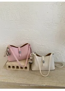 Detail view of leather shoulder bags in pink and beige with gold metal locks