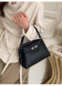 Detailed view of black litchi pattern leather handbag with silver metallic lock closure