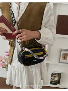Dettaglio borsa Boston con zip gialla e tracolla a motivi geometrici sul modello