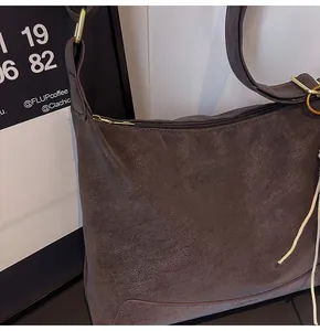 Close-up of retro matte dark coffee shoulder bag with textured leather and gold hardware