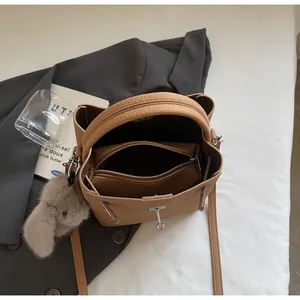 Dettaglio borsa a secchiello color cammello con bustina interna, ciondolo e chiusura a T