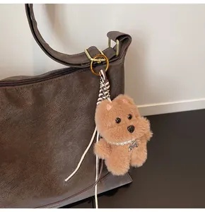 Close-up of plush khaki animal charm with pearl necklace on a brown leather shoulder bag