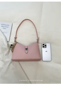 Detail of pink lychee leather handbag with silver clasp and leopard pom-pom charm