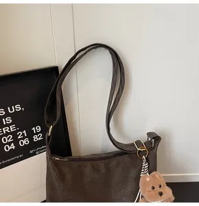 Detail of dark brown matte crossbody bag featuring a cute plush bear charm accessory
