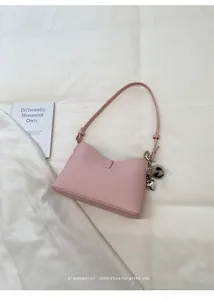Detailed view of pink pebble grain faux leather shoulder bag with heart pendant charm