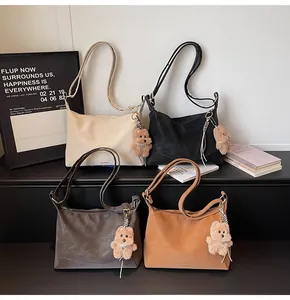 Detail shot of four matte shoulder bags in neutral colors with plush bear charms