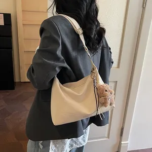 Minimalist beige soft leather crossbody shoulder bag with a cute brown bear charm