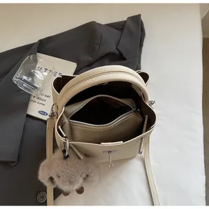 Vista dall'alto di una borsa a secchiello bianco panna con pochette e ciondolo peluche