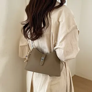 Khaki lychee leather trapezoid shoulder bag with metal clasp and woven knot detail