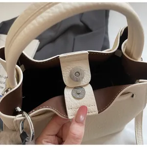 Dettaglio della borsa a secchiello bianco crema con pelle martellata e chiusura magnetica