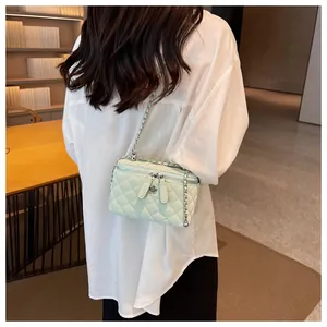 Detailed view of light green quilted crossbody bag with flower charm and silver chain