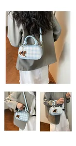 Detalle de bolso bandolera a cuadros azules con asas de cuero y colgante de caballo