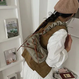 Grey canvas baguette bag with brown bow drawstring details shown on a shoulder