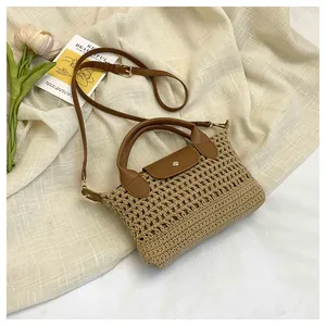 Detail van geweven stro handtas met bruine leren riem en gouden metalen knop