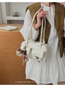Sac à bandoulière vintage blanc crème avec poches avant et breloque ours sur un modèle