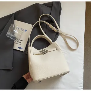 Vista dettagliata della borsa a secchiello in pelle crema con fibbia e piedini protettivi