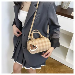 Detalle de bolso Boston a cuadros con asas y colgante de caballo en modelo con blazer gris