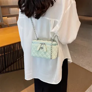 Green quilted leather box bag with silver flower chain strap worn on white shirt
