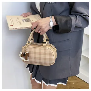 Bolso tipo almohada beige a cuadros con colgante de caballo, llevado por una modelo con traje
