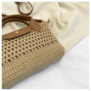 Detail van geweven strohandtas met bruine lederen flap en een gouden metalen sluiting