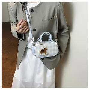 Detalle de bolso bandolera de cuadros azules con colgante de caballo de madera en modelo