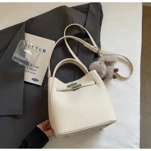 Dettaglio borsa a secchiello in pelle martellata beige con chiusura in metallo e charm