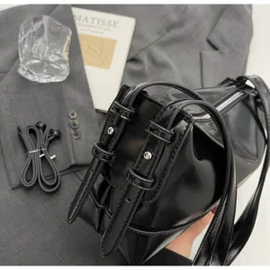 Detail of glossy black leather shoulder bag with silver hardware and adjustable straps