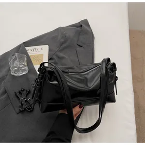 Detail of black pillow shoulder bag showing matte texture and silver zipper closure