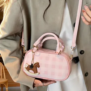 Bolso cilíndrico de cuadros rosas con colgante de caballo y correa ajustable