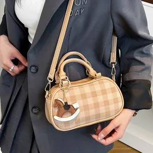 Bolso bandolera beige a cuadros con colgante de caballo llevado por una modelo
