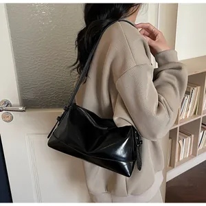 Detail of black glossy faux leather shoulder bag with adjustable side buckle and zipper