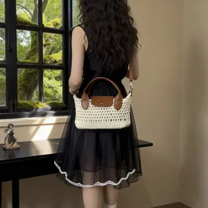 Gevlochten strooien crossbodytas met bruine leren handvatten en klep op een model