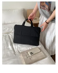 Close-up of black quilted laptop handbag with sturdy handles and waterproof nylon fabric