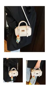 Detail van de crème lederen tas met schattige poppenhanger en parelketting