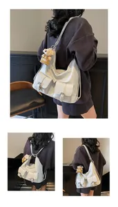 Detail der hellgrauen Hobo-Tasche mit Klapptaschen und braunem Plüschbär-Anhänger