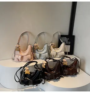 Sechs Schultertaschen im Utility-Stil mit Bärenanhängern auf einem weißen Ausstellungsstand