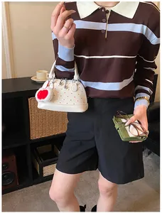 Detailansicht einer weißen Muscheltasche mit roten Punkten und Herzplüsch-Anhänger