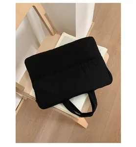 Minimalist black quilted laptop tote bag with padded handles and thick protective texture
