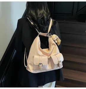 Rückansicht eines beigen Hobo-Rucksacks mit Doppelschnallentaschen und Bärenanhänger