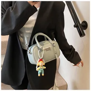 Detail van lichtblauwe leren Boston tas met een cartoon pophanger en metalen logo
