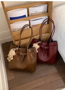 Close-up of minimalist leather tote bags in coffee brown and burgundy with cute bear charm